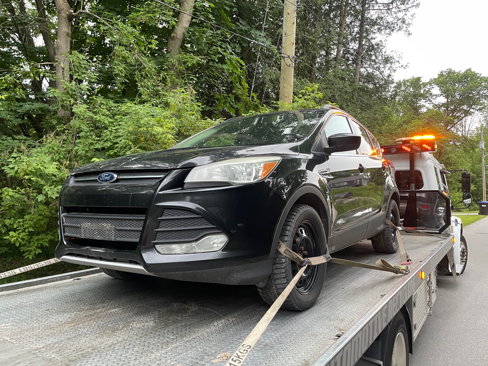 Ford SUV secured to a flatbed tow truck for GTA pickup