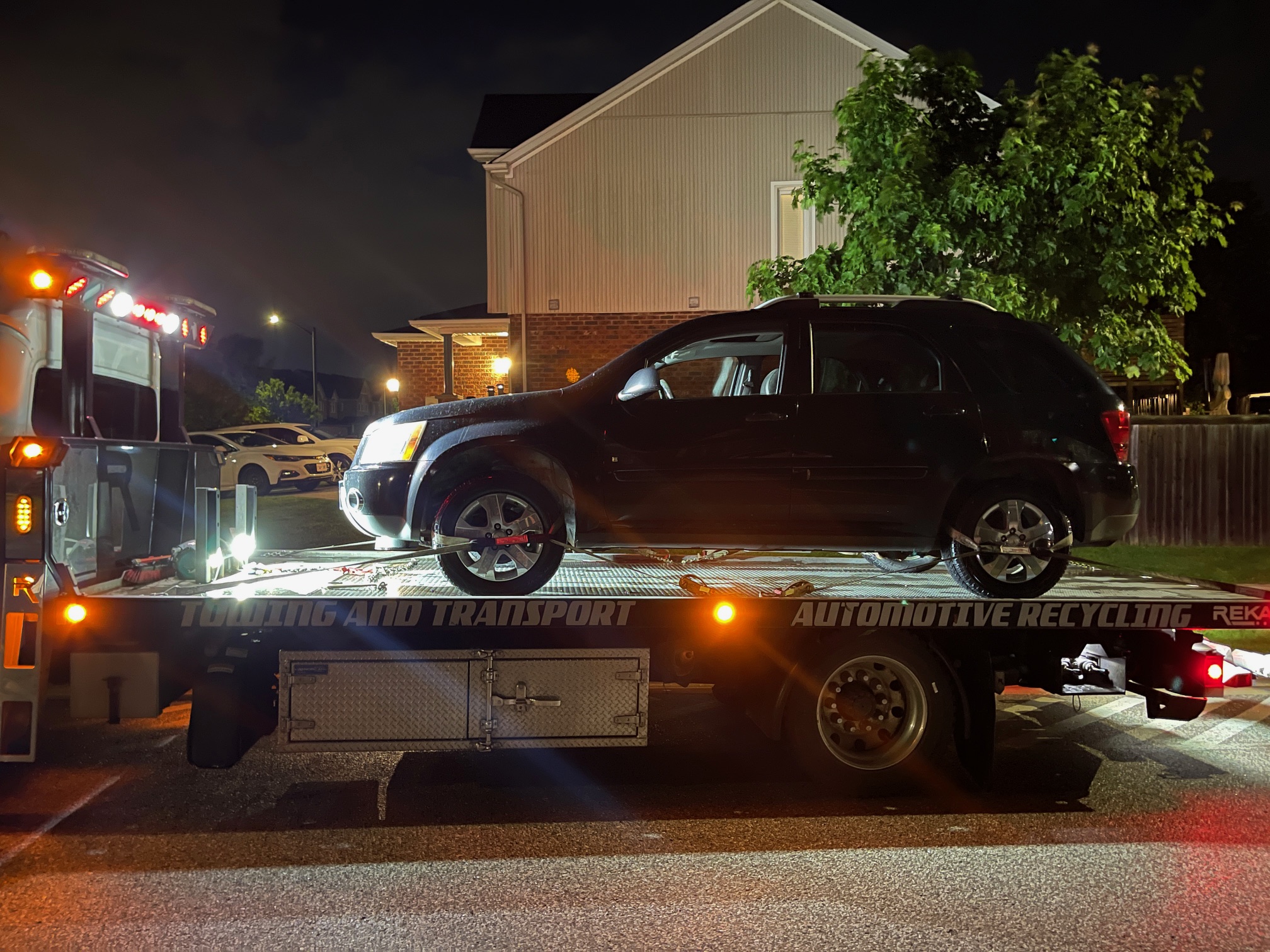 SUV secured on a flatbed during an evening residential pickup