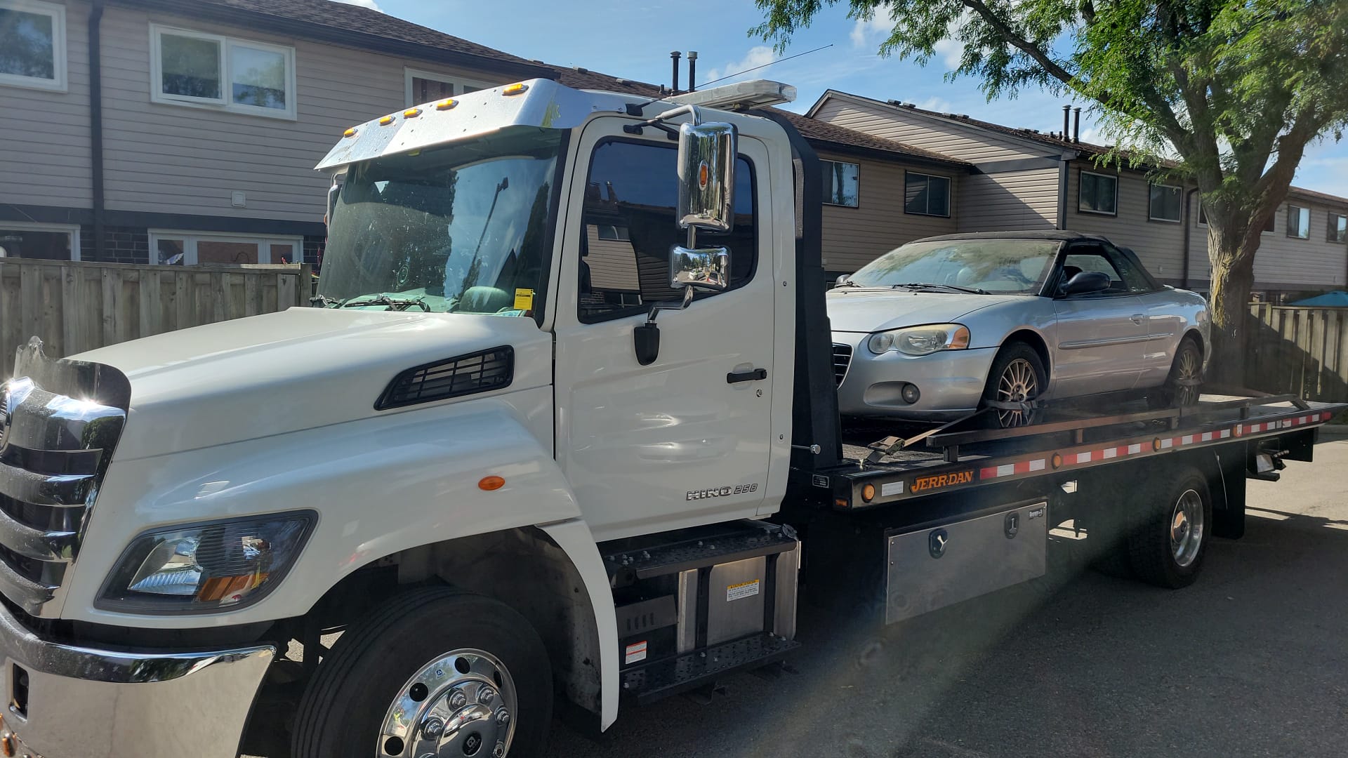 Flatbed tow truck collecting a vehicle from a Toronto driveway