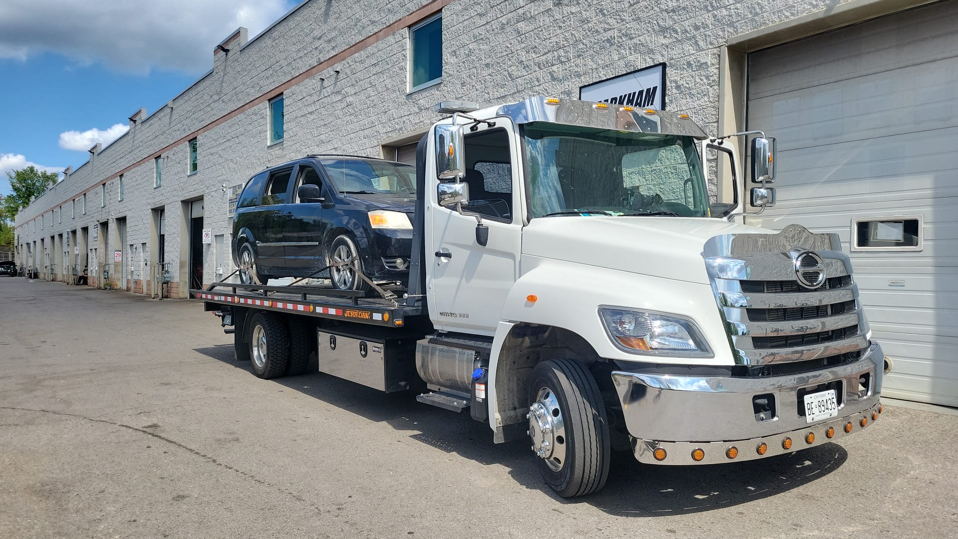 Flatbed tow truck collecting a minivan at a Toronto industrial location