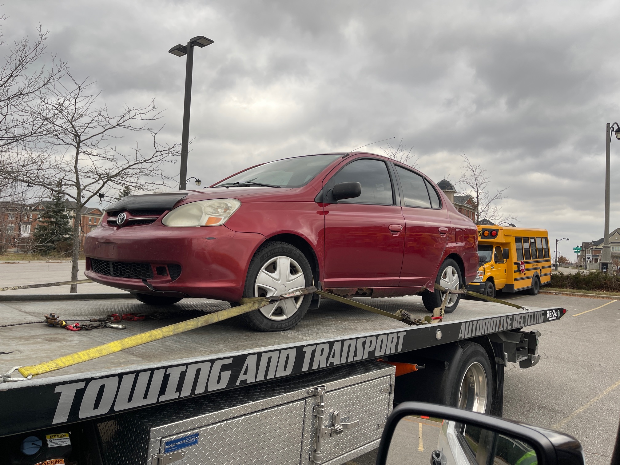 Red Toyota sedan secured to a flatbed truck for vehicle removal